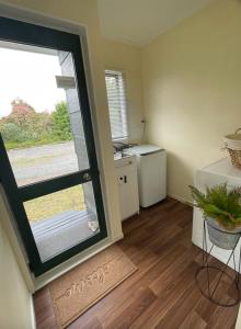 een lege kamer met een deur naar een keuken bij Gordonton Greenmeadows Cottage in Taupiri +7 foto's