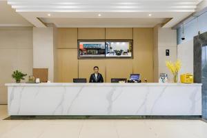 a man sitting at a counter in an office lobby at City Comfort Inn Kunming Dashuying Yejin Hospital Wangdaqiao in Kunming