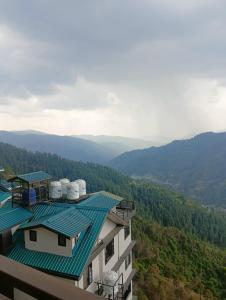 budynek z zielonym dachem z górami w tle w obiekcie Mountain and peace w mieście Shimla