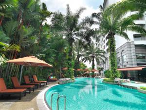 a beach with a pool, chairs, and umbrellas at Sama Sama Hotel KLIA in Sepang