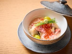 Un tazón de sopa con carne y verduras en una mesa. en Atami Izusan Karaku, en Atami