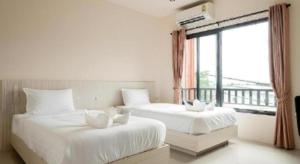 due letti bianchi in una stanza con una finestra di At One Hotel Chiangrai a Ban San Ton Kok