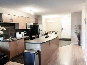 a kitchen with a counter and a sink and a refrigerator at 2 BDRM A/C Condo w/Ensuite Laundry + Free Parking in Edmonton