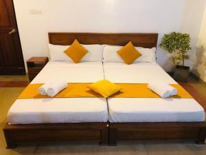 a bed with white sheets and yellow pillows at Borala Lake Weligama in Weligama