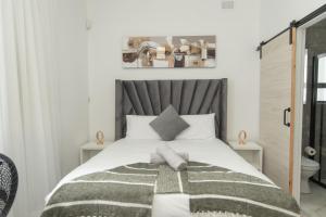 a bedroom with a large bed with a gray headboard at Nine on Second in Gqeberha