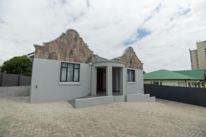 a small white house with a brick building at Nine on Second in Gqeberha