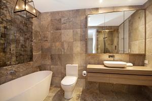 a bathroom with a tub, toilet and sink at Jacaranda Noosa in Noosa Heads