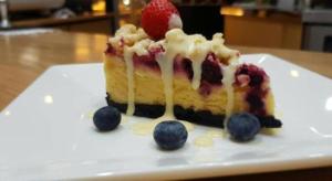 un pezzo di torta con bacche su un piatto bianco di Royal Diamond Hotel a Phetchaburi