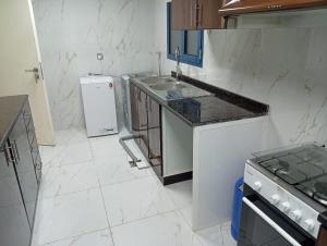 Big Studio In Abu Dhabi Corniche في أبوظبي: مطبخ أبيض مع حوض وثلاجة