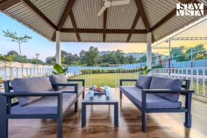 un patio con 2 sedie blu e un tavolo di StayVista at Red Gable with Pool, Lawn a Dhamni