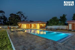 una piscina in un cortile posteriore di notte di StayVista at Red Gable with Pool, Lawn a Dhamni
