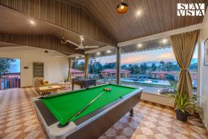 un tavolo da biliardo al centro di una stanza con tavolo da biliardo di StayVista at Red Gable with Pool, Lawn a Dhamni