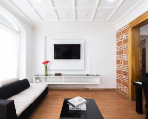 een woonkamer met een witte bank en een tv bij Lumina Ste Presidencial in Cuenca