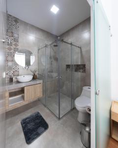 a bathroom with a shower and a toilet and a sink at Lumina Suites in Cuenca