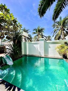 Ban Nong ChaengにあるPool Villa Karaoke Jomtien Pattayaのヤシの木が茂る家の前のスイミングプール