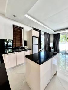 Ban Nong ChaengにあるPool Villa Karaoke Jomtien Pattayaの白いキャビネットと黒いカウンタートップを備えたキッチン