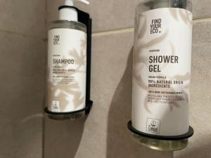 Zwei Flaschen Duschgel stehen an einer Wand. in der Unterkunft Appartement Japandi proche Thermes Cocon Zen Contrexéville in Contrexéville