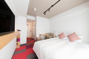 a bedroom with a white bed and a flat screen tv at Tokyu Stay Meguro Yutenji in Tokyo