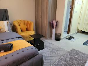 ein Schlafzimmer mit einem Bett und einem Stuhl in einem Zimmer in der Unterkunft Grandmidtown Apartments in Nairobi