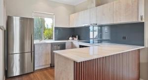 eine Küche mit einem Kühlschrank aus Edelstahl und Holzböden in der Unterkunft Stunning Townhouse on the Foreshore in Victor Harbor