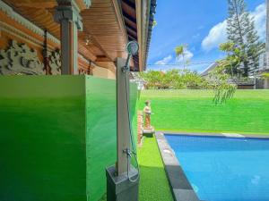 a person standing next to a swimming pool next to a house at The Lavana Kubu Be Long Sanur in Sanur