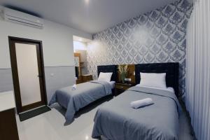 a bedroom with two beds and a mirror at Le Lima in Kuta