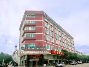 ein hohes rosa Gebäude mit einem Balkon an einer Straße in der Unterkunft GreenTree Alliance Zhejiang Zhoushan Putuoshan Zhujiajian Scenic Spot Hotel in Zhoushan