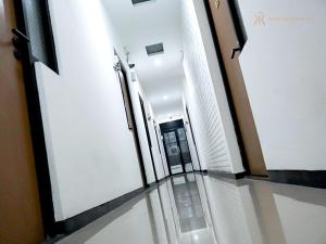 a hallway with white walls and glass floors and doors at Kailash Rooms X Aceh Authentic Resto in Bandung