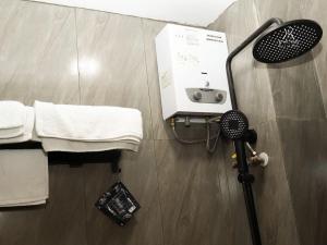 a bathroom with a shower with towels and a fan at Kailash Rooms X Aceh Authentic Resto in Bandung