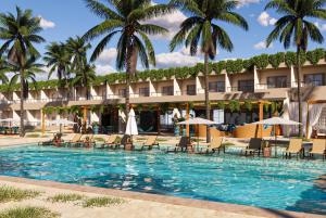 einen Pool im Resort mit Stühlen und Palmen in der Unterkunft Wyndham Natal Pitangui Praia in Extremóz