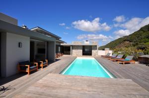 a swimming pool with chairs and a house at Cliffhanger Estate in Keurboomstrand