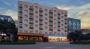 ein großes rosa Gebäude vor einem Gebäude in der Unterkunft Zhangye Pinmu Hotel(Yuncheng Zhongyin Avenue Store) in Yuncheng