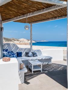 a patio with white furniture and the beach at Aerides Mandrakia Milos in Mandrakia