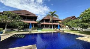 a swimming pool in front of a house at Tulamben Wreck Divers Resort & Restaurant in Tulamben