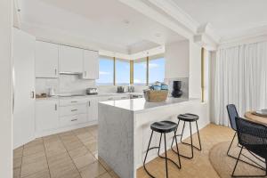 a kitchen with white cabinets and a counter with stools at Luxury 3BR Gold Coast Stay Ocean and City Views in Gold Coast