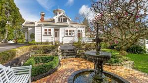 a white house with a fountain in the yard at Mt Eden Victorian Villa in Auckland