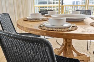a wooden table with chairs and coffee cups on it at Luxury 3BR Gold Coast Stay Ocean and City Views in Gold Coast