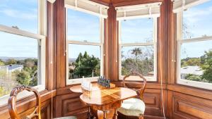 a dining room with windows and a wooden table and chairs at Mt Eden Victorian Villa in Auckland +11 photos