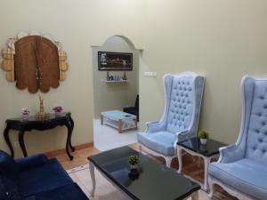 a living room with two blue chairs and a table at Nariska Suite Homestay in Yogyakarta