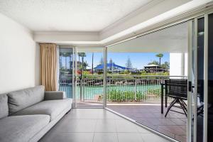 Una sala de estar con un sofá y una puerta corrediza de vidrio. en Poolside Escape at Alexandra Headland, en Alexandra Headland