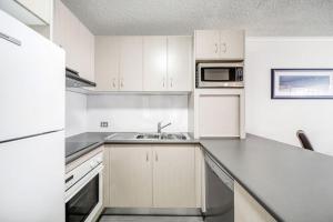 Una cocina con gabinetes blancos y un fregadero. en Poolside Escape at Alexandra Headland, en Alexandra Headland