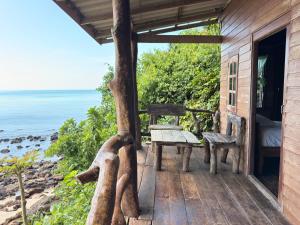 eine Veranda eines Hauses mit einer Bank und dem Meer in der Unterkunft Ao Siri Beach Bungalow in Ko Jum