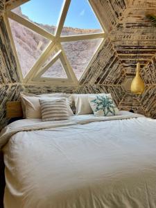 a bedroom with a large bed with a large window at Mannam desert dome in Dahab +6 photos