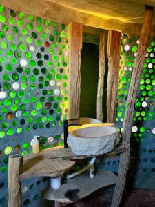 a bathroom with a sink and a wall of green bottles at Mannam desert dome in Dahab