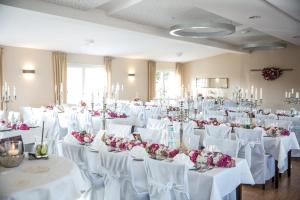 Hotel Drei Linden في Twist: غرفة مليئة بالطاولات البيضاء والكراسي مع الزهور