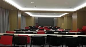 a conference room with red chairs and a screen at Echarm Hotel Jinan Railway Station Daming Lake in Jinan