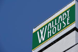 a green and white sign on the side of a building at Wallaby House in Kawaguchi