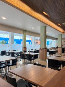 ein Esszimmer mit Tischen und Stühlen und Fenstern in der Unterkunft Alltrue Lite Hotel Nagoya Hill Batam in Nagoya