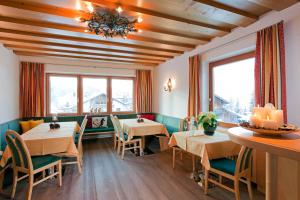 ein Restaurant mit Tischen und Stühlen und Fenstern in der Unterkunft Apart Faldershof in Fiss