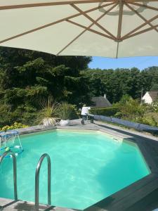 una grande piscina con ombrellone di L'Eugenie a Pierrefonds